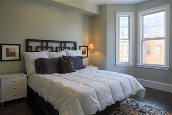 A bedroom with a bed, nightstand and window.
