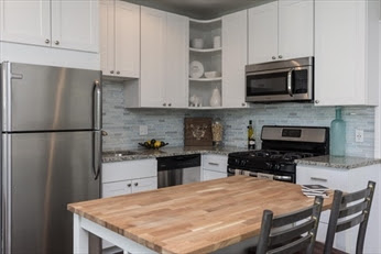 A kitchen with white cabinets and stainless steel appliances.