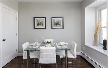 A dining room table with four chairs and two framed pictures.