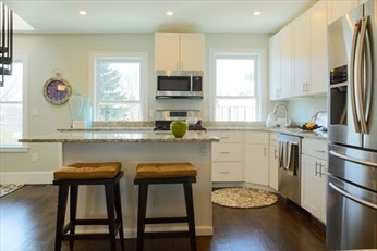 A kitchen with white cabinets and brown stools